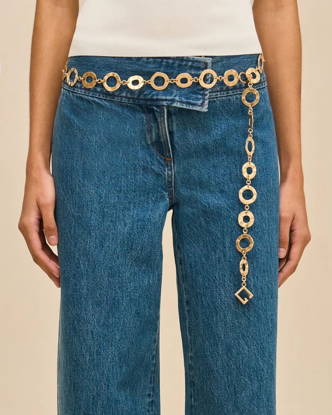 Cult Gaia belt | Michael Hayes Newport | Michael Hayes Newport Gold circular-link belt over blue jeans with a long dangling chain and square charm at the hip